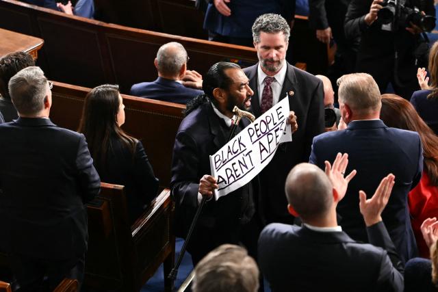 US Representative Al Green, Democratic from Texas, exits as he holds a sign reading "Black people aren't apes" as US President Donald Trump delivers the State of the Union address in the House Chamber of the US Capitol in Washington, DC, on February 24, 2026. (Photo by ANDREW CABALLERO-REYNOLDS / AFP)