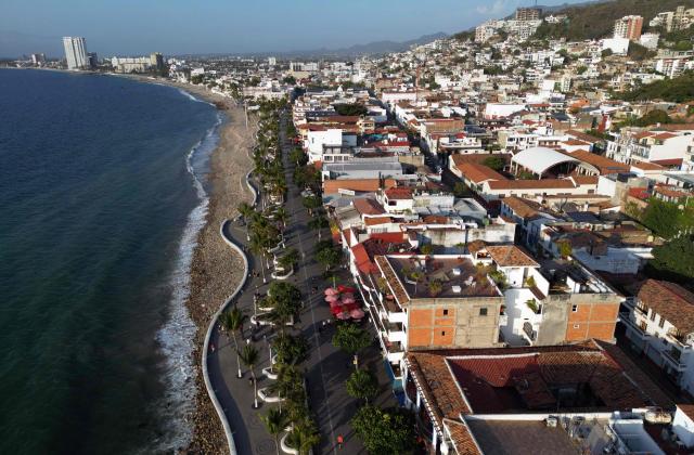 This aerial view shows people walking on the coastline of Puerto Vallarta, Jalisco state, Mexico on February 24, 2026. Known as a sunny tourist paradise, parts of the coastal city of Puerto Vallarta seem more like the set of a war film in the aftermath of violent chaos spurred by the capture and death of Mexico's most-wanted drug lord Nemesio "El Mencho" Oseguera. (Photo by Alfredo ESTRELLA / AFP)