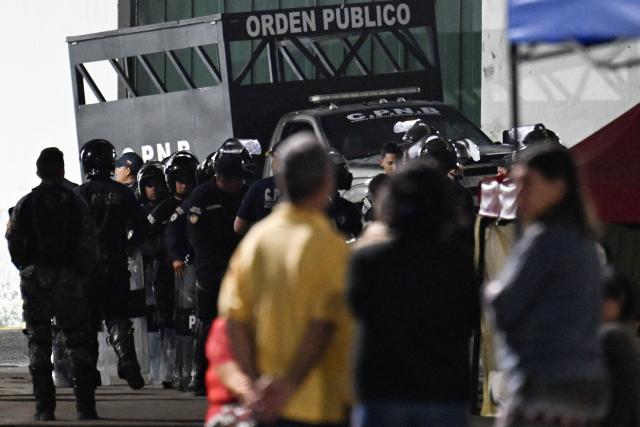 Venezuelan riot police officers stand guard during a protest by relatives of political prisoners outside the Zone 7 prison of the Bolivarian National Police (PNB) in Caracas on February 24, 2026. A total of 179 political prisoners were released from prison in Venezuela under the recently enacted amnesty law, Parliament reported on February 24, as complaints mount about delays in processing the benefit in the courts. (Photo by Juan BARRETO / AFP)