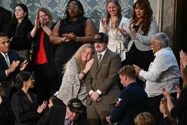 National Guard Staff Sgt. Andrew Wolfe (C, in hat), who survived a November 2025 shooting in Washington, DC, stands as he is recognized by US President Donald Trump as he delivers the State of the Union address in the House Chamber of the US Capitol in Washington, DC, on February 24, 2026. (Photo by ANDREW CABALLERO-REYNOLDS / AFP)