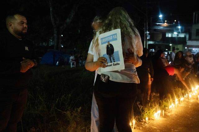 A relative holds a sign depicting imprisoned Argentine gendarme Nahuel Agustin Gallo during a vigil by relatives of political prisoners outside El Rodeo I prison in Guatire, Miranda state, Venezuela, on February 24, 2026. A total of 179 political prisoners were released from prison in Venezuela under the recently enacted amnesty law, Parliament reported on February 24, as complaints mount about delays in processing the benefit in the courts. (Photo by Maryorin Mendez / AFP)