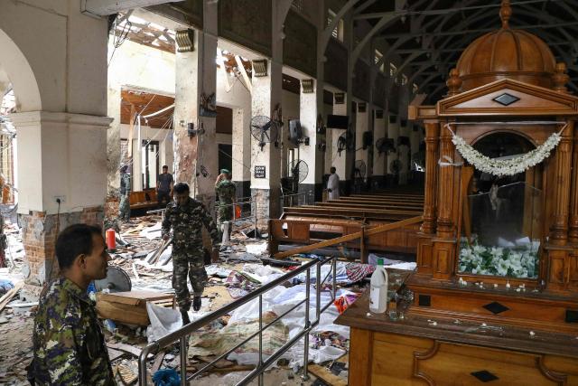 (FILES) Sri Lankan security personnel walk past dead bodies covered with blankets amid blast debris at St. Anthony's Shrine following an explosion in the church in Kochchikade in Colombo on April 21, 2019. Sri Lanka's criminal investigators arrested the country's former intelligence chief Suresh Sallay on February 25, 2026 in connection with the 2019 Easter Sunday bombings that killed 279 people, police said. (Photo by ISHARA S.  KODIKARA / AFP)