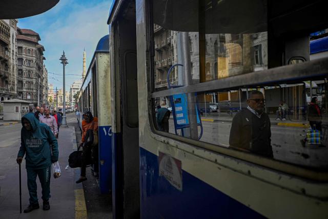 Commuters step off a tram in the coastal city of Alexandria on February 18, 2026. Along Egypt's Mediterranean coast, the oldest tram in Africa and the Middle East rumbles for a final few weeks before its removal -- the latest urban upheaval Alexandrians say is hollowing out their city's identity. Inaugurated in 1863, the tram is one of the world's oldest, and among only a few to operate double-decker cars. (Photo by Khaled DESOUKI / AFP)