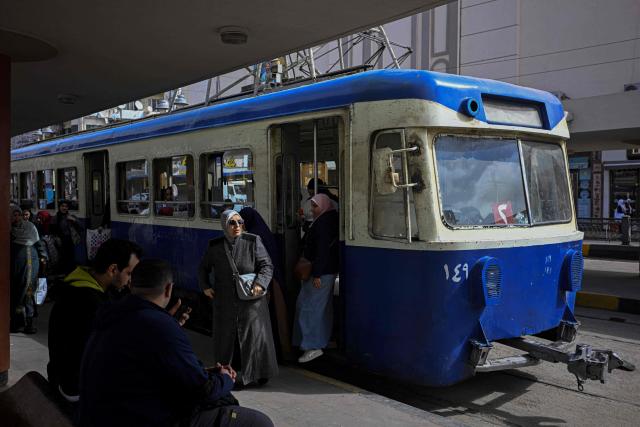 Commuters step off a tram in the coastal city of Alexandria on February 18, 2026. Along Egypt's Mediterranean coast, the oldest tram in Africa and the Middle East rumbles for a final few weeks before its removal -- the latest urban upheaval Alexandrians say is hollowing out their city's identity. Inaugurated in 1863, the tram is one of the world's oldest, and among only a few to operate double-decker cars. (Photo by Khaled DESOUKI / AFP)