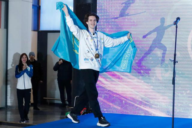 Kazakhstan's Olympic gold medallist Mikhail Shaidorov enters the podium during an official welcoming ceremony to mark his arrival from the Milano Cortina 2026 Winter Olympic Games at the airport in Astana on February 25, 2026. (Photo by Stanislav Filippov / AFP)