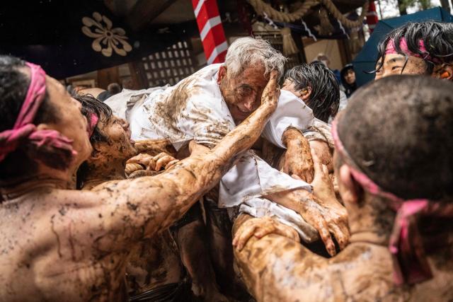 Participants hold up a man and smear mud on his face during the Warabi Hadaka festival at Mimusubi shrine in Yotsukaido, Chiba Prefecture on February 25, 2026. (Photo by Yuichi YAMAZAKI / AFP)