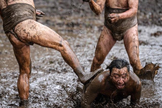 A participant is kicked into a muddy field during the Warabi Hadaka festival in Yotsukaido, Chiba Prefecture on February 25, 2026. (Photo by Yuichi YAMAZAKI / AFP)