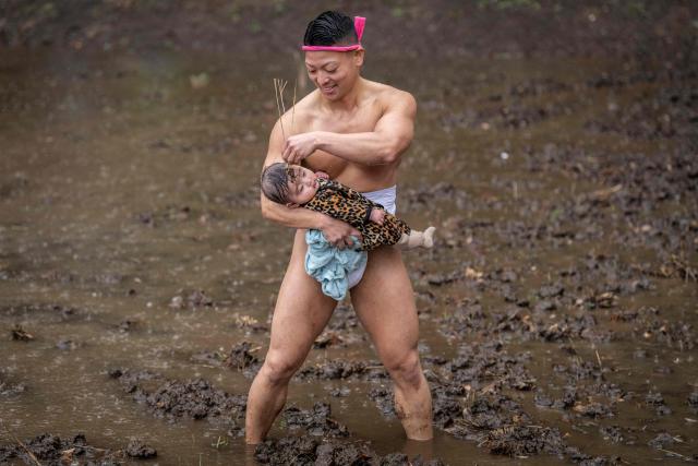 A participant applies mud to a baby's forehead to pray for healthy growth during the Warabi Hadaka festival in Yotsukaido, Chiba Prefecture on February 25, 2026. (Photo by Yuichi YAMAZAKI / AFP)