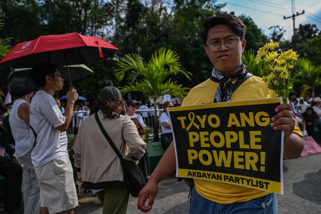 A man holds a banner saying “We are the People Power” as he joins an anti-corruption rally that coincides with the 40th anniversary of the EDSA People Power Revolution, in Quezon City on February 25, 2026. (Photo by Jam STA ROSA / AFP)