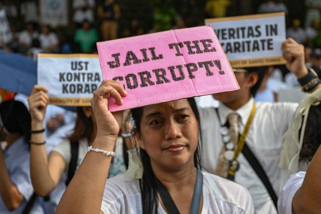 A woman holds a banner saying “Jail the Corrupt” as she joins an anti-corruption rally that coincides with the 40th anniversary of the EDSA People Power Revolution, in Quezon City on February 25, 2026. (Photo by Jam STA ROSA / AFP)