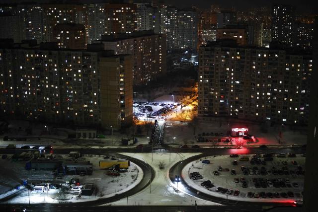 A car drives in a residential area of the Pozniaky district in Kyiv on February 22, 2026, amid the Russian invasion of Ukraine. As Ukraine accuses Russia of trying to freeze the population into submission with its most intense attacks on the energy network of the entire war, more and more people in Kyiv are fundraising and pooling cash to buy alternative sources of shared electricity. (Photo by HENRY NICHOLLS / AFP)