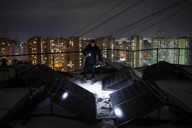 Chairman of the Board of the Association of Co-Owners of the Apartment Building 'Dzherelo' Denys Biletsky, 42, inspects solar panels on the rooftop of a residential building, which has been suffering from heating and power outages, in the Pozniaky district of Kyiv on February 22, 2026, amid the Russian invasion of Ukraine. As Ukraine accuses Russia of trying to freeze the population into submission with its most intense attacks on the energy network of the entire war, more and more people in Kyiv are fundraising and pooling cash to buy alternative sources of shared electricity. (Photo by HENRY NICHOLLS / AFP)