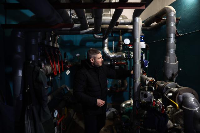 Chairman of the Board of the Association of Co-Owners of the Apartment Building 'Dzherelo' Denys Biletsky, 42, inspects the equipment in the hot water pumping room of the apartment complex, which has been suffering from heating and power outages, in the Pozniaky district of Kyiv on February 22, 2026, amid the Russian invasion of Ukraine. As Ukraine accuses Russia of trying to freeze the population into submission with its most intense attacks on the energy network of the entire war, more and more people in Kyiv are fundraising and pooling cash to buy alternative sources of shared electricity. (Photo by HENRY NICHOLLS / AFP)