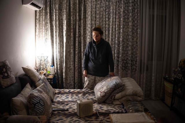 Local resident Tetyana Kolisnichenko, 47, stands in her apartment that often suffers from loss of heating and power in the Berezniaky district of Kyiv on February 19, 2026, amid the Russian invasion of Ukraine. As Ukraine accuses Russia of trying to freeze the population into submission with its most intense attacks on the energy network of the entire war, more and more people in Kyiv are fundraising and pooling cash to buy alternative sources of shared electricity. (Photo by HENRY NICHOLLS / AFP)