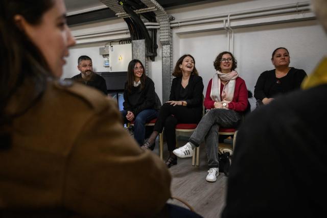 Psychiatrist Nathalie Bounhoure (C) sits with patients following rehearsals of the Toulouse orchestra as part of the 'Résonance(s)' project to promote their recovery, at the Halle aux Grains theatre in Toulouse Southwestern France on February 10, 2026. The project was launched in 2023 through a partnership between the renowned Orchestre National du Capitole and several mental health institutions in the region. Its aim, in the face of conditions that can trap patients in a negative self-image, is to allow them to attend four rehearsals a year to initiate a process of reconnecting with others and the outside world, and simply to promote their recovery. (Photo by Ed JONES / AFP) / TO GO WITH AFP STORY BY Valentin GRAFF