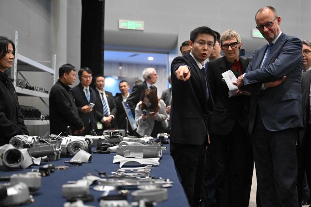 German Chancellor Friedrich Merz (R), accompanied by Unitree Robotics CEO Wang Xingxing (3rd R) visits a showroom of Unitree Robotics products in Hangzhou, in eastern China’s Zhejiang Province on February 26, 2026. Merz arrived in the Chinese tech hub of Hangzhou on February 26 with a large group of entreprenuers, hoping to land new contracts a day after meeting President Xi Jinping and announcing an Airbus deal. (Photo by Jade Gao / AFP)