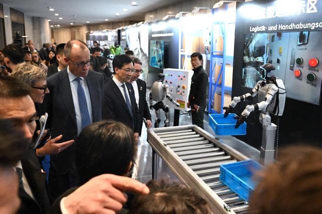 German Chancellor Friedrich Merz (3rd L) visits a showroom of Unitree Robotics products in Hangzhou, in eastern China’s Zhejiang Province on February 26, 2026. Merz arrived in the Chinese tech hub of Hangzhou on February 26 with a large group of entreprenuers, hoping to land new contracts a day after meeting President Xi Jinping and announcing an Airbus deal. (Photo by Jade Gao / AFP)