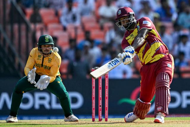 West Indies' Romario Shepherd (R) plays a shot as South Africa's wicketkeeper Quinton de Kock watches during the 2026 ICC Men's T20 Cricket World Cup Super Eights match between West Indies and South Africa at Narendra Modi Stadium in Ahmedabad on February 26, 2026. (Photo by Indranil MUKHERJEE / AFP)