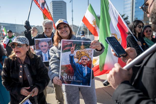 Protestors react and hold portraits of Reza Pahlavi II during a demonstration organised by members of the Iranian diaspora outside the United Nations offices during new round of talks between the United States and Iran on Iran’s nuclear program, in Geneva on February 26, 2026. (Photo by Fabrice COFFRINI / AFP)
