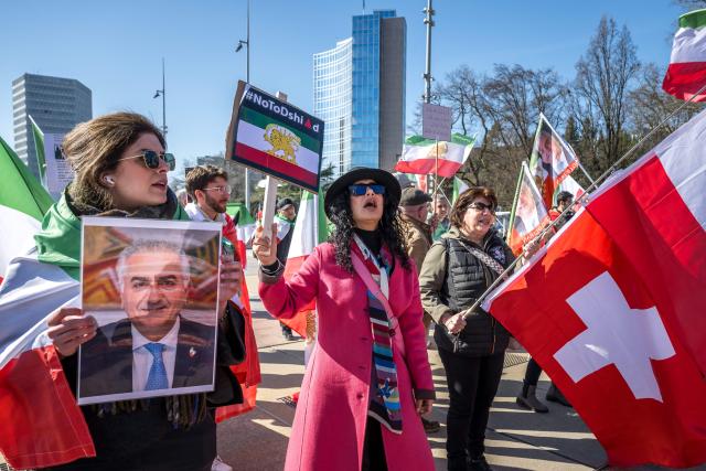 Protestors react and hold portraits of Reza Pahlavi II during a demonstration organised by members of the Iranian diaspora outside the United Nations offices during new round of talks between the United States and Iran on Iran’s nuclear program, in Geneva on February 26, 2026. (Photo by Fabrice COFFRINI / AFP)