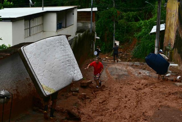 Residents remove belongings after flooding and landslides in the Los Tres Molinos neighborhood in Juiz de Fora, Minas Gerais state, Brazil, on February 26, 2026. Despair hung over two cities in southeastern Brazil on February 25 as rescuers and residents searched for 21 people missing after torrential rains unleashed flooding and landslides that killed at least 46. (Photo by Pablo PORCIUNCULA / AFP)
