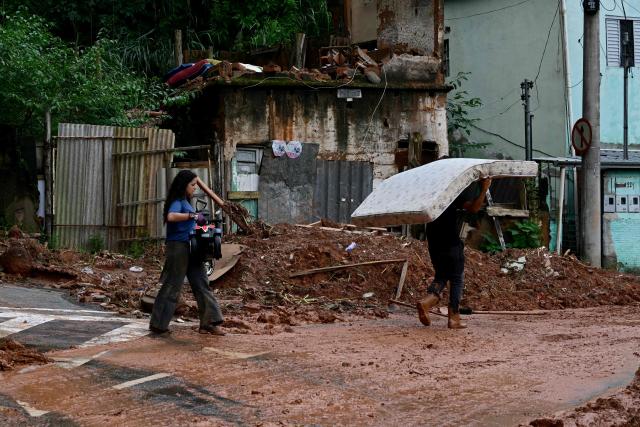 Residents remove belongings after flooding and landslides in the Los Tres Molinos neighborhood in Juiz de Fora, Minas Gerais state, Brazil, on February 26, 2026. Despair hung over two cities in southeastern Brazil on February 25 as rescuers and residents searched for 21 people missing after torrential rains unleashed flooding and landslides that killed at least 46. (Photo by Pablo PORCIUNCULA / AFP)