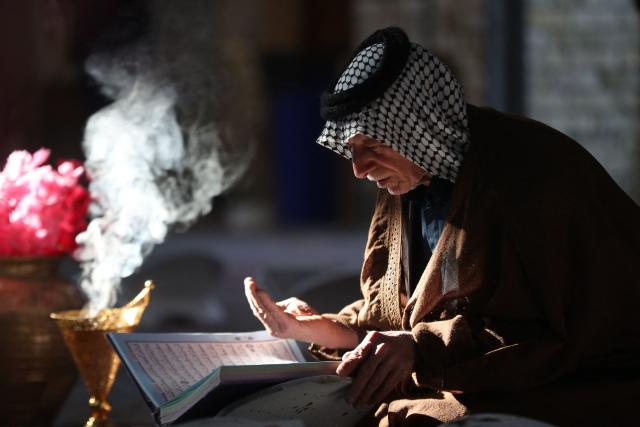 TOPSHOT - A man reads and recites the Koran at a recitation ceremony during the holy fasting month of Ramadan at the shrine of Imam al-Qasim ibn Imam Musa al-Kadhim, south of the city of Hilla, Babil Governorate, central Iraq on February 25, 2026. (Photo by Karrar Jabbar / AFP)