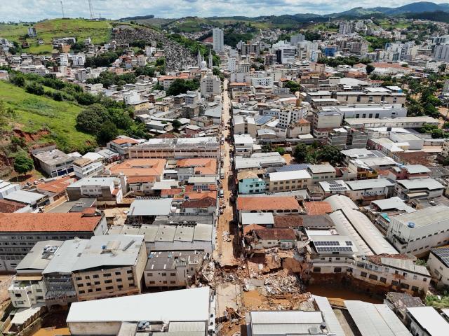 TOPSHOT - Aerial view showing streets of the commercial district of Uba, in Minas Gerais State, Brazil, on February 25, 2026, where a bridge and several buildings collapsed after the Uba River overflowed due to heavy rains. Despair hung over two cities in southeastern Brazil on February 25 as rescuers and residents searched for 27 people missing after torrential rains unleashed flooding and landslides that killed at least 40. (Photo by Pablo PORCIUNCULA / AFP)