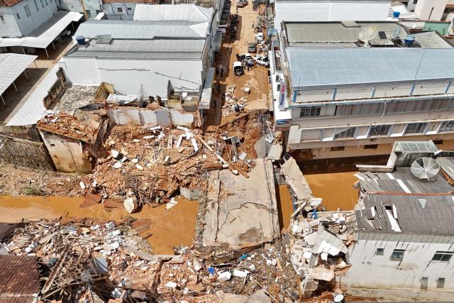 TOPSHOT - Aerial view showing streets of the commercial district of Uba, in Minas Gerais State, Brazil, on February 25, 2026, where a bridge and several buildings collapsed after the Uba River overflowed due to heavy rains. Despair hung over two cities in southeastern Brazil on February 25 as rescuers and residents searched for 27 people missing after torrential rains unleashed flooding and landslides that killed at least 40. (Photo by Pablo PORCIUNCULA / AFP)