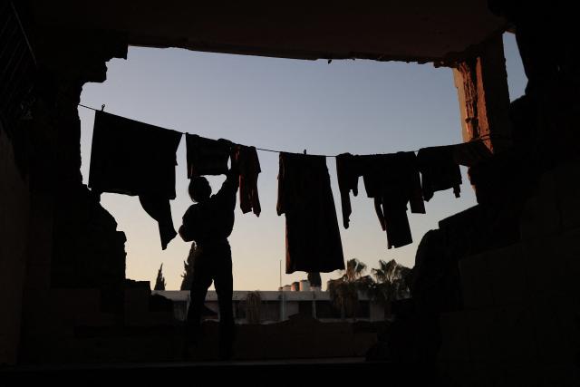 TOPSHOT - A displaced Palestinian woman habds laundry before taking the "iftar" fast-breaking meal during the Muslim holy month of Ramadan, amidst the destruction in Bureij refugee camp in the central Gaza Strip on February 25, 2026. (Photo by Eyad Baba / AFP)