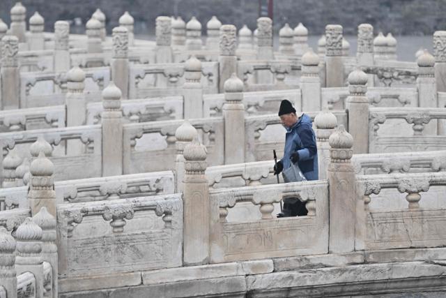 TOPSHOT - A worker cleans a bridge ahead of German Chancellor Friedrich Merz's visit to the Forbidden City in Beijing on February 26, 2026. (Photo by Pedro PARDO / AFP)