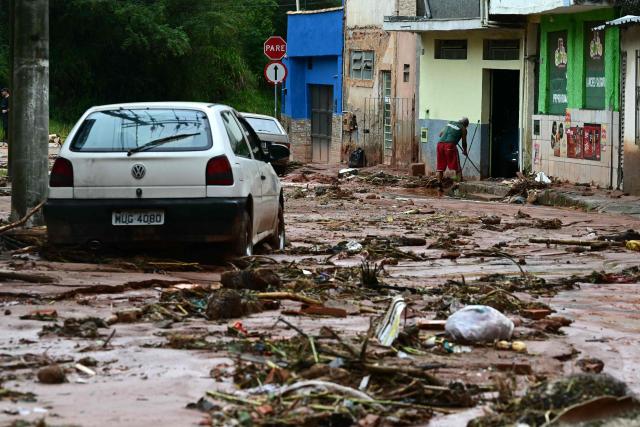 A resident cleans mud and debris after heavy rainfall in the Los Tres Molinos neighborhood in Juiz de Fora, Minas Gerais state, Brazil, on February 26, 2026. Despair hung over two cities in southeastern Brazil on February 25 as rescuers and residents searched for 21 people missing after torrential rains unleashed flooding and landslides that killed at least 46. (Photo by Pablo PORCIUNCULA / AFP)