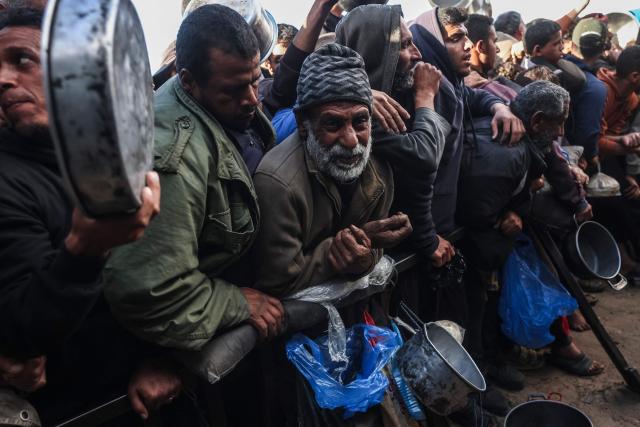 Palestinians wait to receive food at a soup kitchen in Khan Yunis, in the southern Gaza Strip on February 26, 2026. Despite a US-brokered ceasefire that entered its second phase last month, shortages remain in Gaza, whose battered economy and material damage have rendered most residents at least partly dependent on humanitarian aid for their basic needs. (Photo by BASHAR TALEB / AFP)