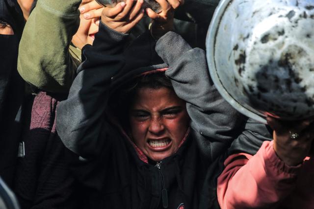 A Palestinian child reacts while waiting to receive food at a soup kitchen in Khan Yunis, in the southern Gaza Strip on February 26, 2026. Despite a US-brokered ceasefire that entered its second phase last month, shortages remain in Gaza, whose battered economy and material damage have rendered most residents at least partly dependent on humanitarian aid for their basic needs. (Photo by BASHAR TALEB / AFP)