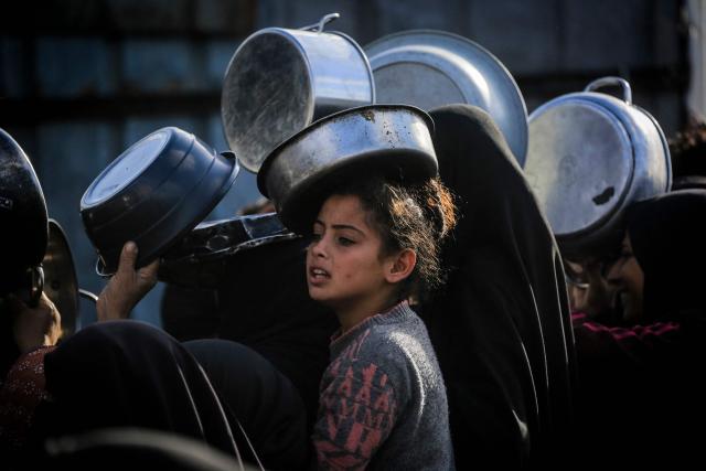 Palestinians wait to receive food at a soup kitchen in Khan Yunis, in the southern Gaza Strip on February 26, 2026. Despite a US-brokered ceasefire that entered its second phase last month, shortages remain in Gaza, whose battered economy and material damage have rendered most residents at least partly dependent on humanitarian aid for their basic needs. (Photo by BASHAR TALEB / AFP)