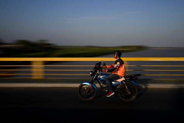 A man rides a motorbike on the Maria Nieves bridge in San Fernando de Apure, Apure State, Venezuela, on February 26, 2026. (Photo by Federico PARRA / AFP)