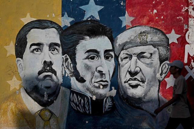 A man walks past a mural of Venezuelan ousted President Nicolas Maduro, Venezuelan independence hero Simon Bolivar and the late  Venezuelan President Hugo Chavez in San Fernando de Apure, on February 26, 2026. (Photo by Federico PARRA / AFP)