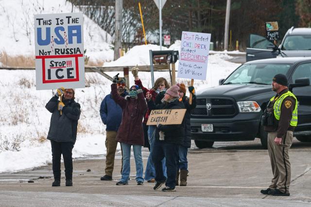 Demonstrators hold up signs as the motorcade of US Vice President JD Vance departs after he spoke at Pointe Precision, a machining facility in Plover, Wisconsin, on February 26, 2026 (Photo by Matt Rourke / POOL / AFP)