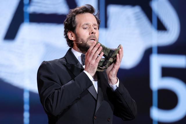 French actor Benjamin Lavernhe puts on the mask from the movie The Mask during the 51st edition of the Cesar Film Awards ceremony at the Olympia venue in Paris on February 26, 2026. (Photo by Thomas SAMSON / AFP)