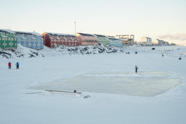 People walk near a frozen lake beside newly built residental housing in Nuuk, Greenland, on February 26, 2026. Greenland’s economy is primarily focused on fishing, but with the United States’ growing interest in the country, its prospects appear to be diversifying. However, specialists warn that this could lead to economic imbalance for the Arctic island. (Photo by Florent VERGNES / AFP)