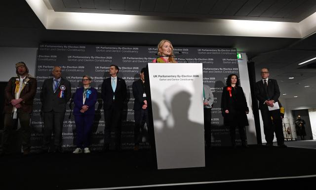 Reform UK candidate Matt Goodwin (4L) and Labour party candidate Angeliki Stogia (2R) listen as Green Party candidate Hannah Spencer gives her acceptance speech after winning the Gorton and Denton Parliamentary by-election, at Manchester Central Convention Complex in Manchester, northern England on February 27, 2026. (Photo by Paul ELLIS / AFP)