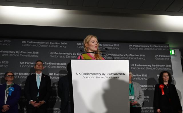 Reform UK candidate Matt Goodwin (2L) and Labour party candidate Angeliki Stogia (R) listen as Green Party candidate Hannah Spencer gives her acceptance speech after winning the Gorton and Denton Parliamentary by-election, at Manchester Central Convention Complex in Manchester, northern England on February 27, 2026. (Photo by Paul ELLIS / AFP)
