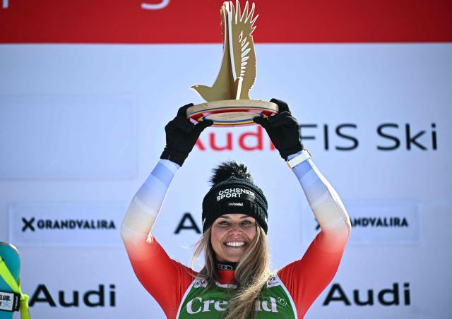 First-placed Switzerland's Corinne Suter lifts her trophy on the podium after winning the women's downhill race, part of the FIS Alpine Ski World Cup 2025-2026 in Soldeu, Andorra on February 26, 2026. (Photo by Lionel BONAVENTURE / AFP)