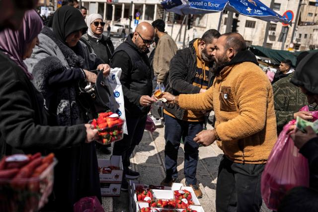 People buy strawberries from a produce vendor after the second Friday noon prayers of the holy month of Ramadan in the old city of Jerusalem on February 27, 2026. Muslims throughout the world are marking the month of Ramadan, the holiest month in the Islamic calendar, during which devotees fast from dawn until dusk. (Photo by JOHN WESSELS / AFP)