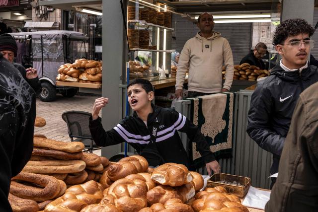 People buy bread after the second Friday noon prayers of the holy month of Ramadan in the old city of Jerusalem on February 27, 2026. Muslims throughout the world are marking the month of Ramadan, the holiest month in the Islamic calendar, during which devotees fast from dawn until dusk. (Photo by JOHN WESSELS / AFP)