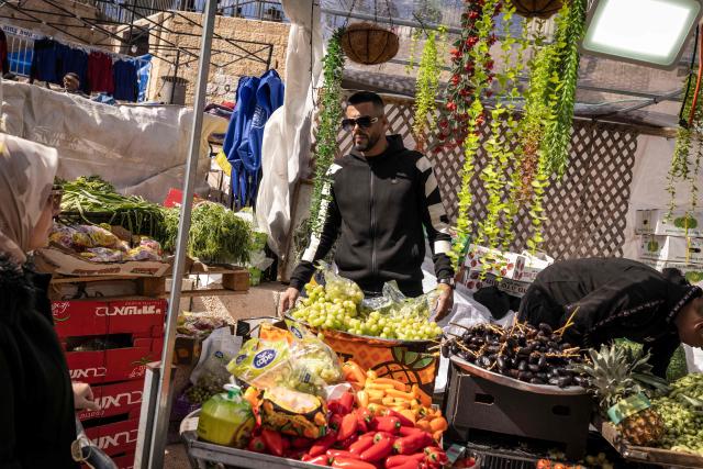 A produce vendor sells fruit and vegetables from a stall after the second Friday noon prayers of the holy month of Ramadan in the old city of Jerusalem on February 27, 2026. Muslims throughout the world are marking the month of Ramadan, the holiest month in the Islamic calendar, during which devotees fast from dawn until dusk. (Photo by JOHN WESSELS / AFP)