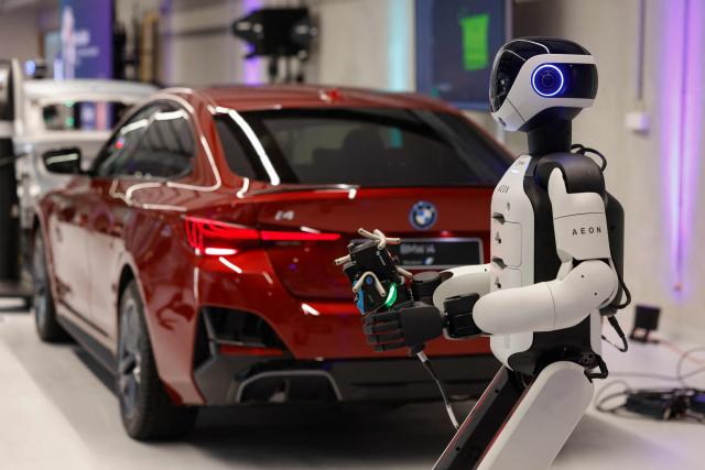 AEON, a humanoid robotic created by the company Hexagon, works on a car with a laser scanner, as it is presented by BMW is presented by BMW, at their BMW Group Talent Campus in Munich, Bavaria, southern Germany, on February 27, 2026. (Photo by Michaela STACHE / AFP)