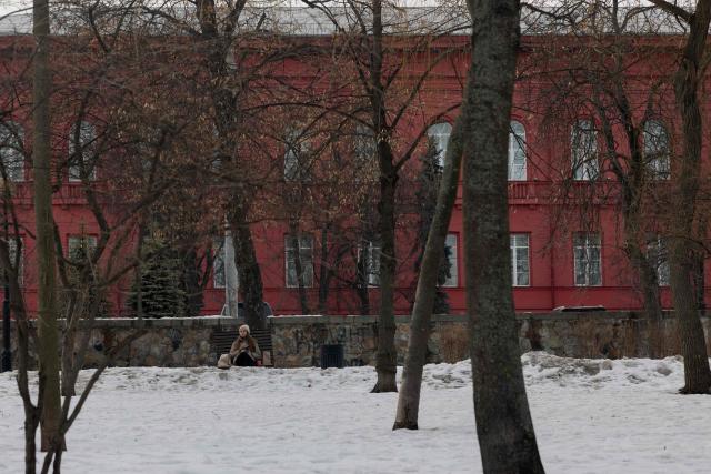A members of the public sits on a bench in a snowy park in Kyiv on February 27, 2026, amid the Russian invasion of Ukraine. (Photo by Tetiana DZHAFAROVA / AFP)