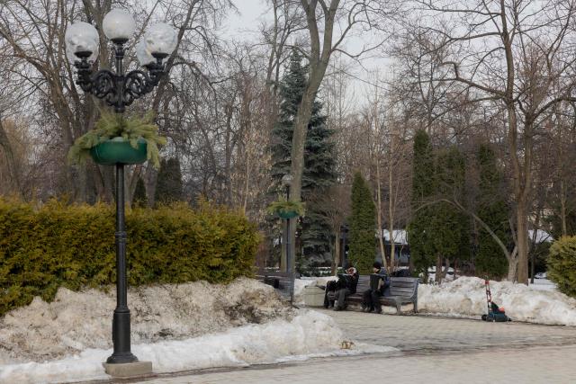 Street musicians sit on a bench in a snowy park in Kyiv on February 27, 2026, amid the Russian invasion of Ukraine. (Photo by Tetiana DZHAFAROVA / AFP)