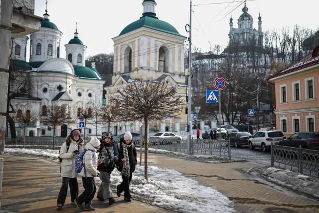 Youths walks near the Intercession Church in the Podil district of Kyiv on February 27, 2026, amid the Russian invasion of Ukraine. (Photo by HENRY NICHOLLS / AFP)